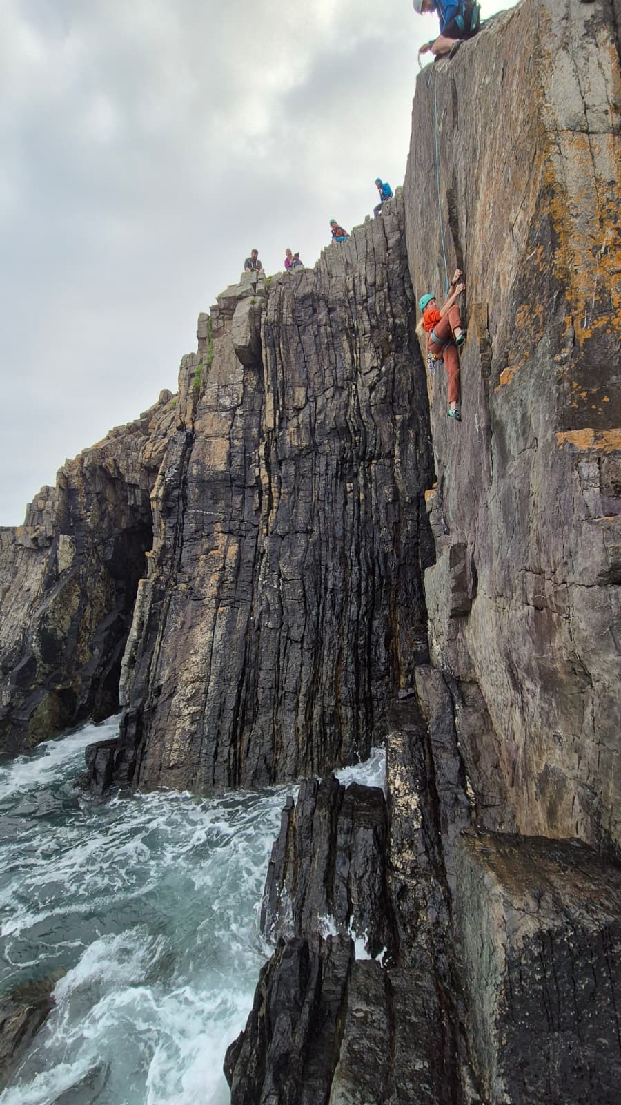 A climber climbing a dramatic cliff at organs pipes north pembrokeshire.